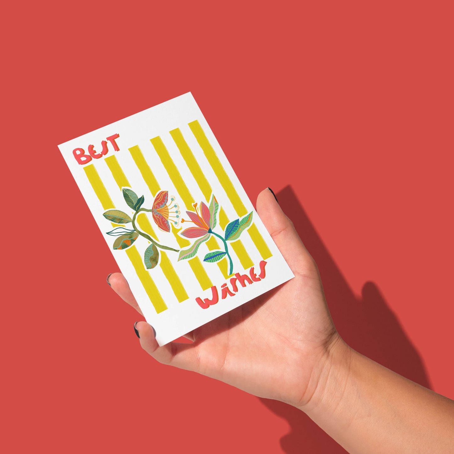 Hand holding a card with floral design and text against a red background