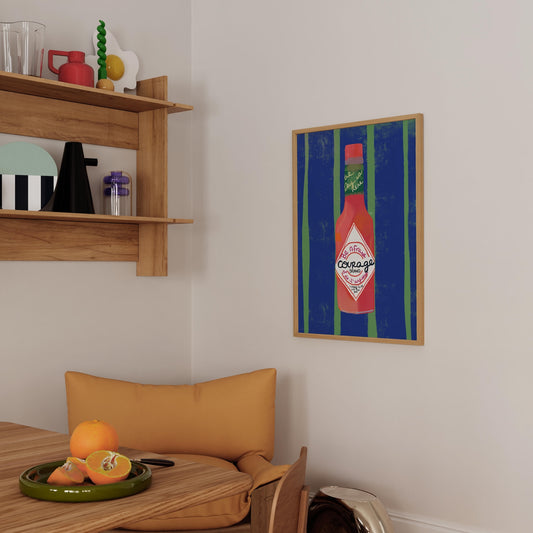 Framed artwork of a ketchup bottle on a wall above a wooden chair with a cushion.