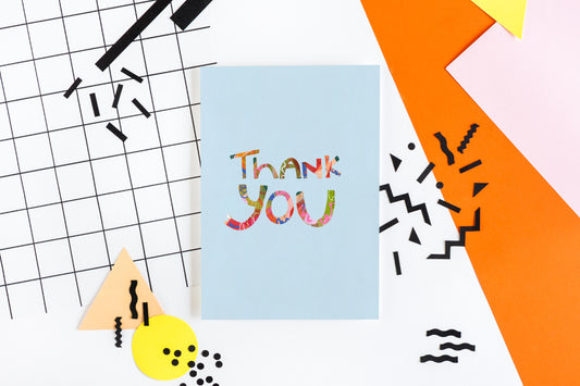 A greeting card with blue background and a colorful thank you