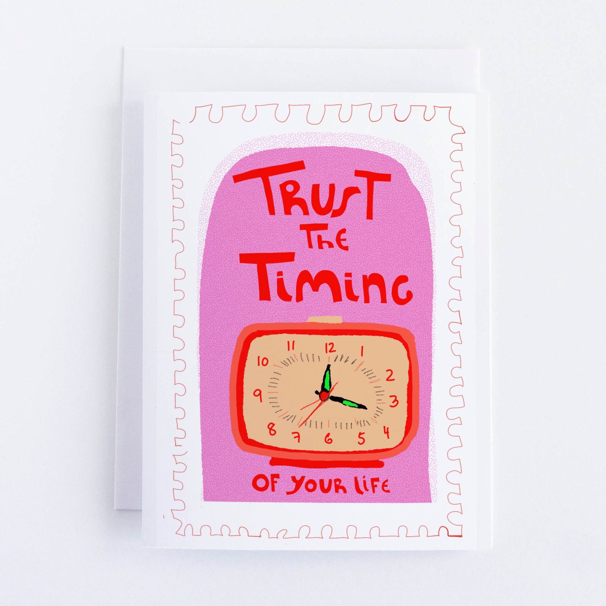 Greeting card with a pink background featuring an illustration of a clock and the text 'TRUST THE TIMING OF YOUR LIFE'. An envelope is included.