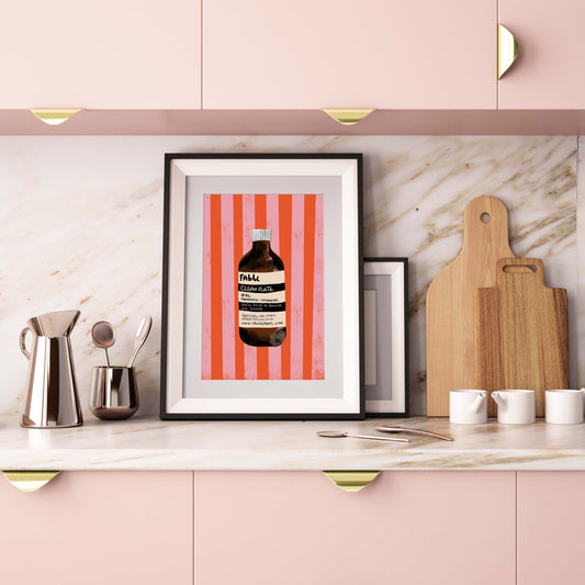 Framed artwork on a kitchen counter with pink cabinets and marble backsplash.
