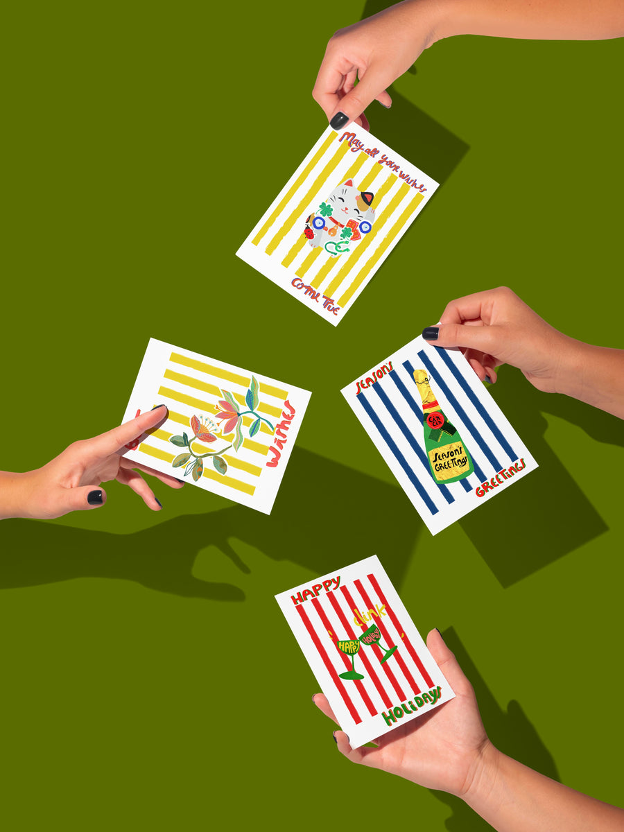 Four hands holding greeting cards with different designs on a green background