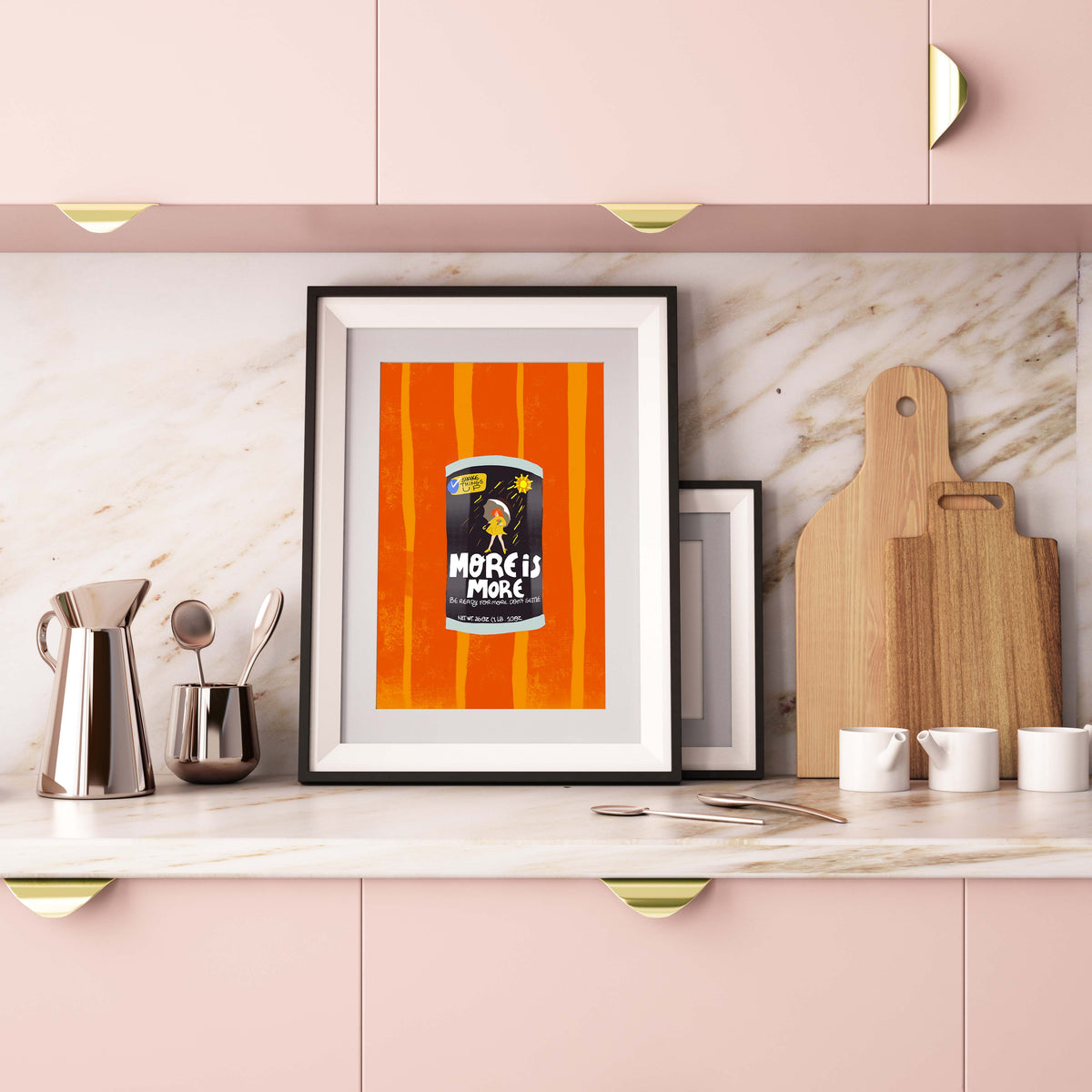 Framed artwork on a kitchen counter with pink cabinets and marble backsplash.