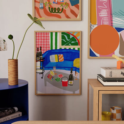Vibrant art print of a blue sofa with Uno cards, champagne bottles on a cart, and a red ice bucket. Bold checkered and striped maximalist wall decor.
