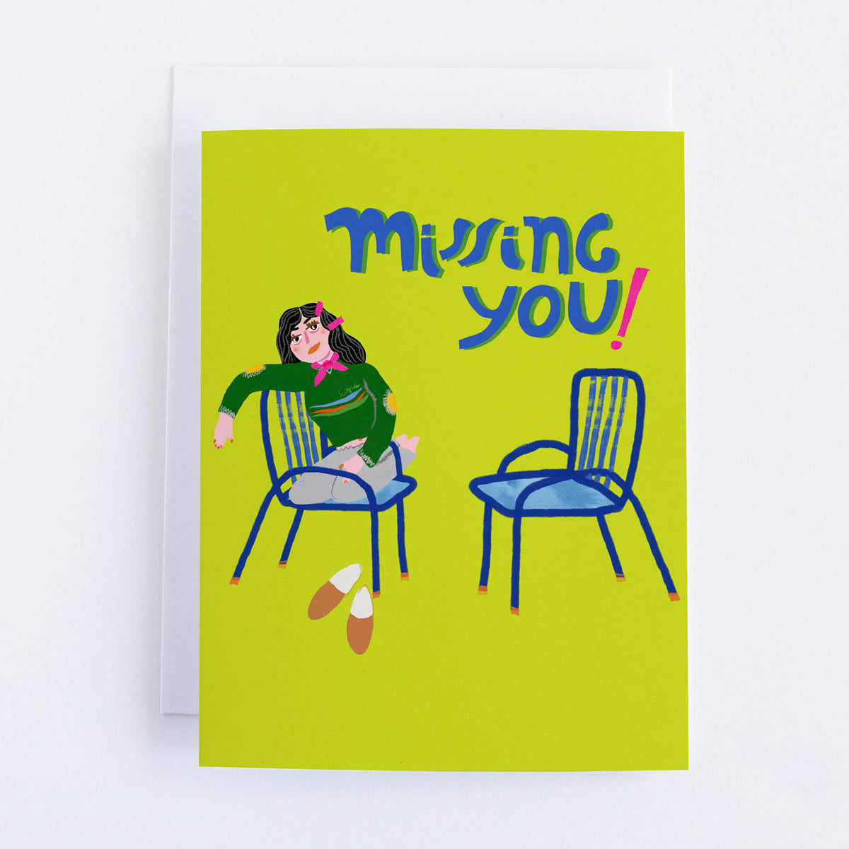 A greeting card with a yellow background featuring an illustration of a person sitting on a chair with a text 'Missing you!'